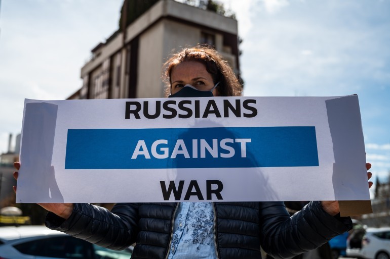 A woman holds a banner in front of the Russian embassy in Madrid to protest against the Russian invasion of Ukraine [File: Marcos del Mazo/LightRocket via Getty Images]